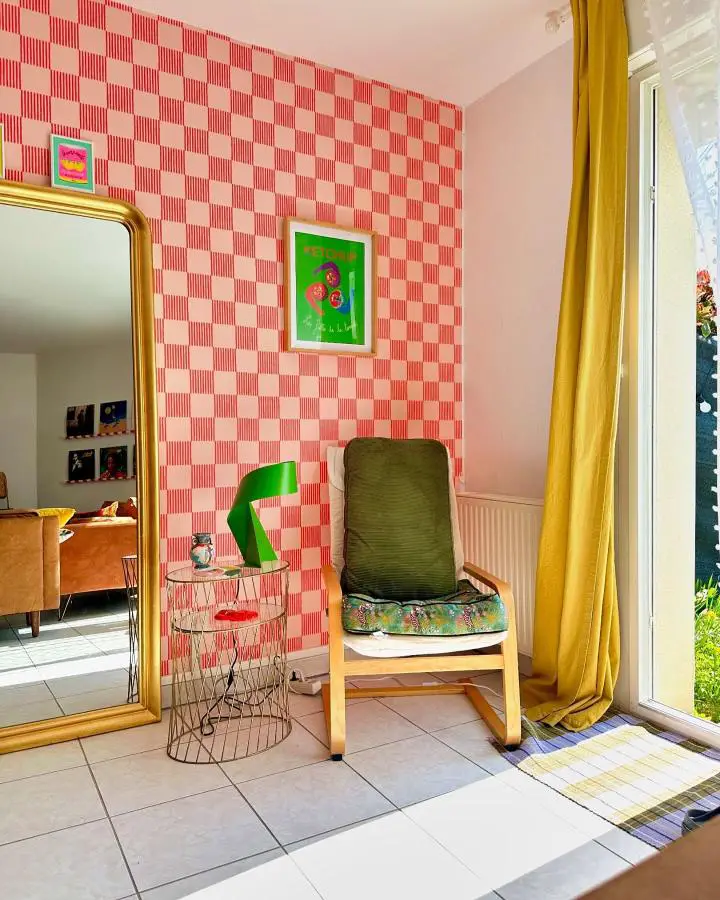 Checkerboard wallpaper bedroom corner from @manonl.delahaute featuring retro pink and red geometric patterns with yellow accents.