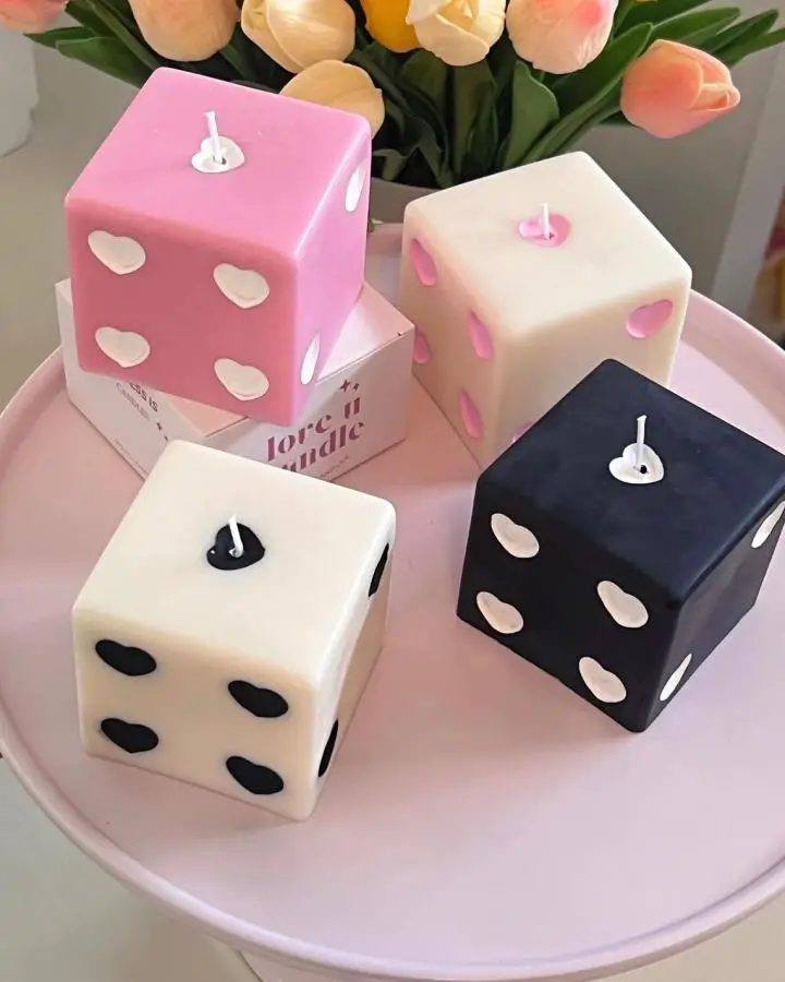 Colorful dice-shaped candles from LOVEUCANDLE arranged on pink tray with tulips in background.