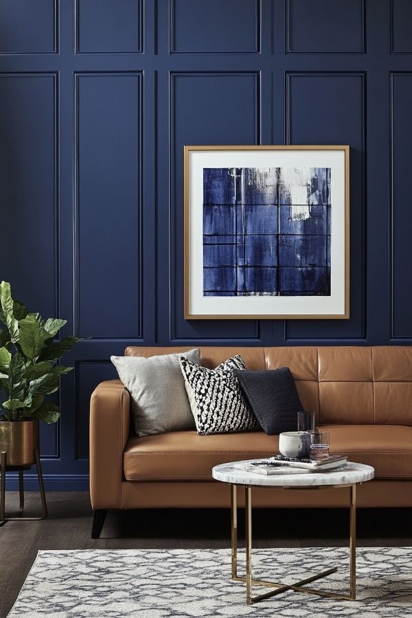 A wall-mounted wooden shelf holding plants and framed art.