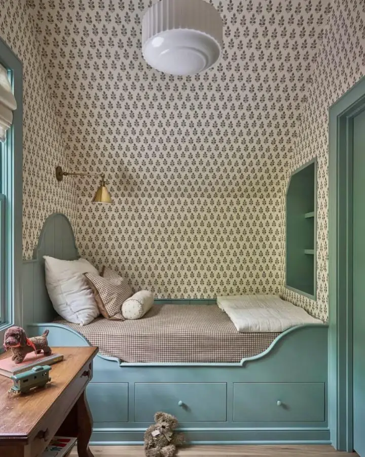 Sage green built-in daybed nook from @lucycunninghaminteriors with small-scale patterned wallpaper and coordinating painted trim.