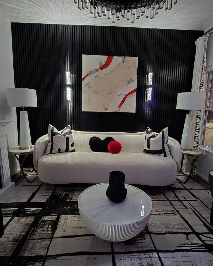 Black slatted textured wall with white modern sofa and abstract art by @homebodywithforlisa featuring bold monochrome and red accents in a stylish living room.