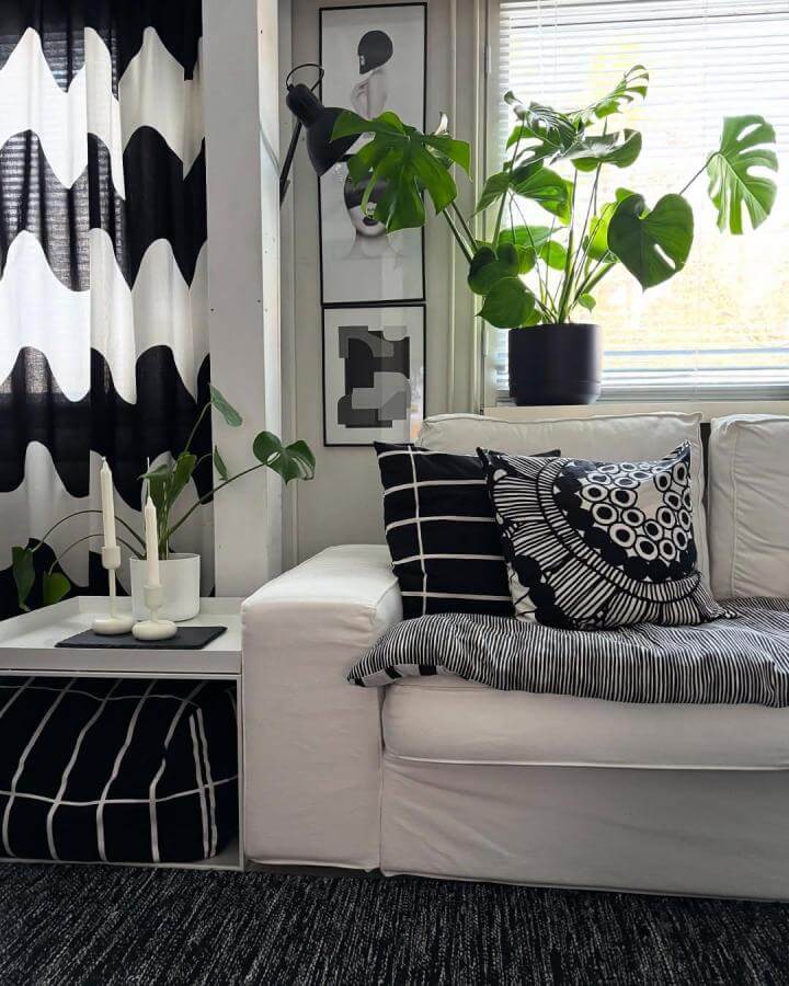 Black and white patterned curtains and textiles with green plants decorate a modern living room from @kotokuvia highlighting black and white living room ideas.
