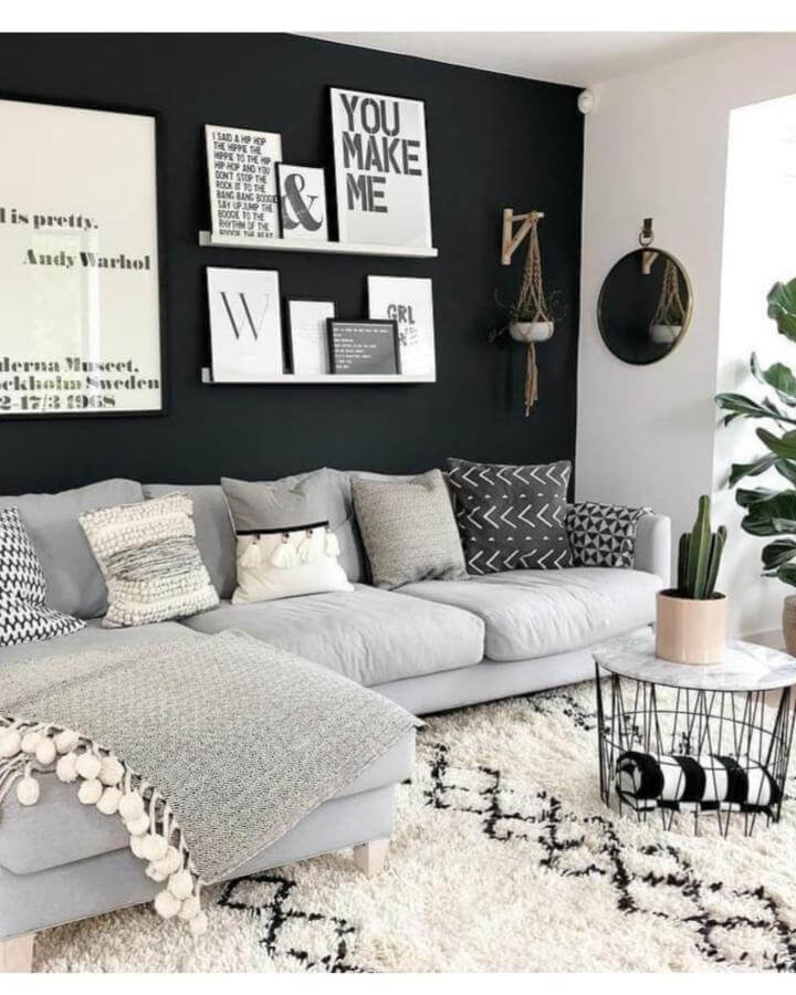 Grey sectional with black accent wall and patterned cushions from @lucyjwhitehouse. Cozy layered neutrals with modern monochrome art and décor.