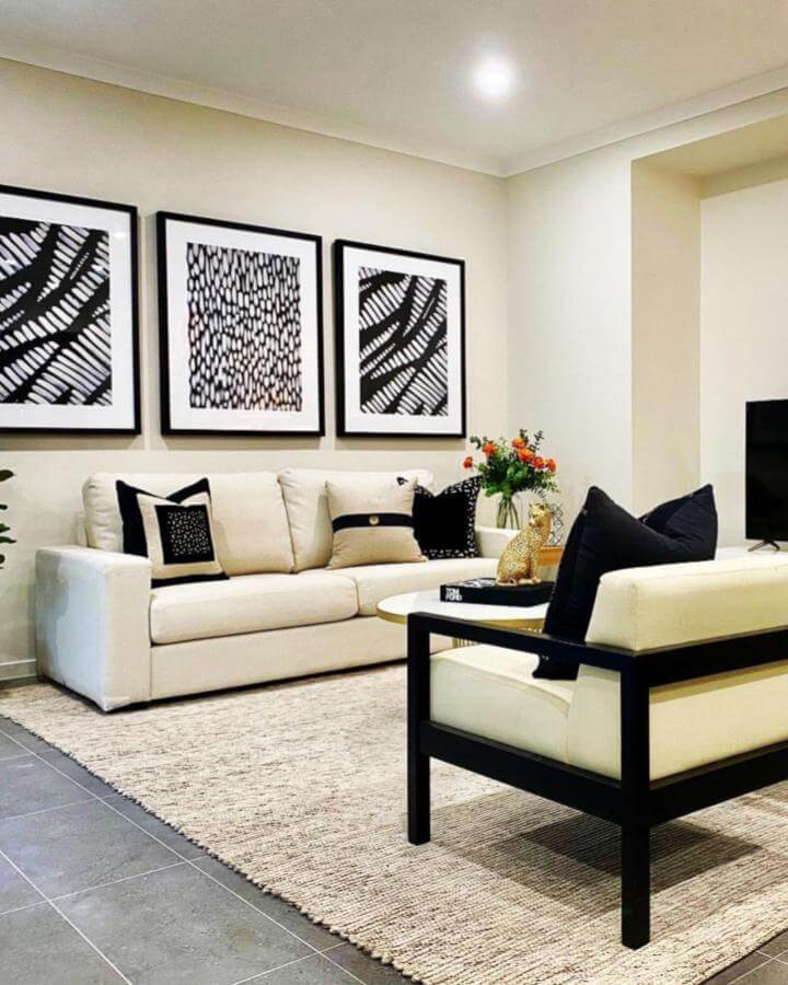 Cream sofa and armchair with bold black accents from @kelliehobbsinteriors. Black framed abstract art and textured rug enhance elegant monochrome style.