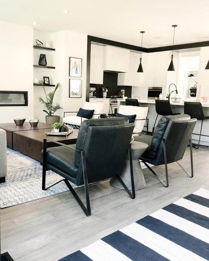 Black leather chairs and striped rug in a modern open living room by @lushinteriorsyyc showcase sharp monochrome style.