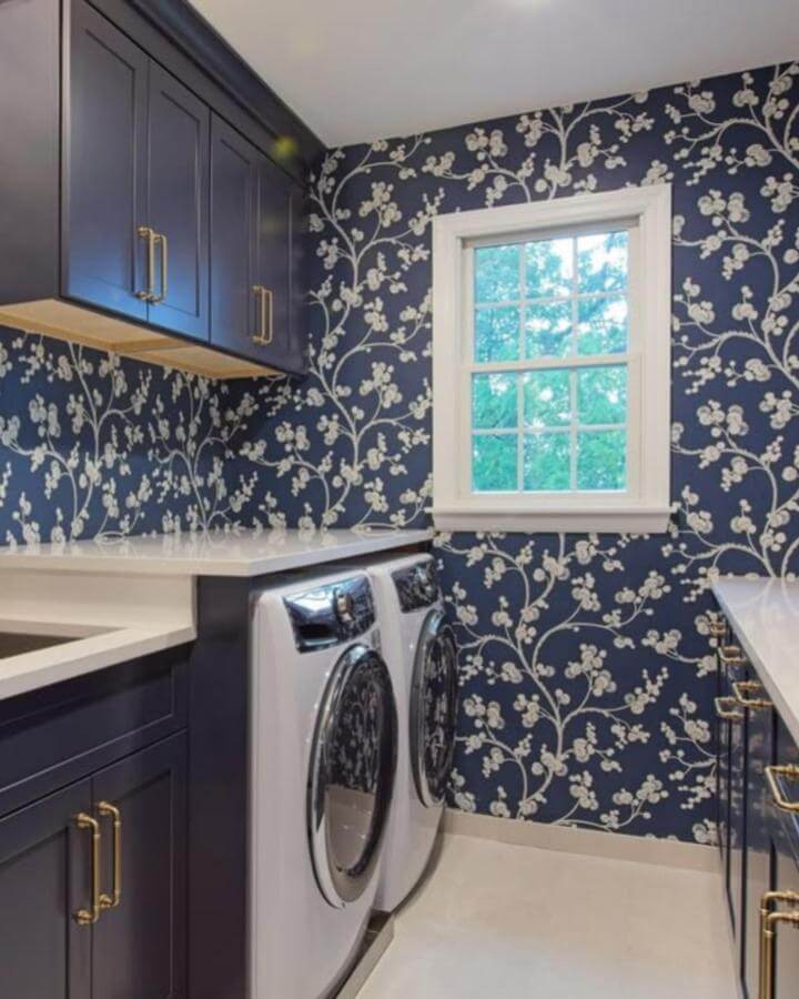 Alt text: Navy floral wallpaper and cabinetry laundry room from @butterandvelvet_design featuring elegant blue laundry room ideas.