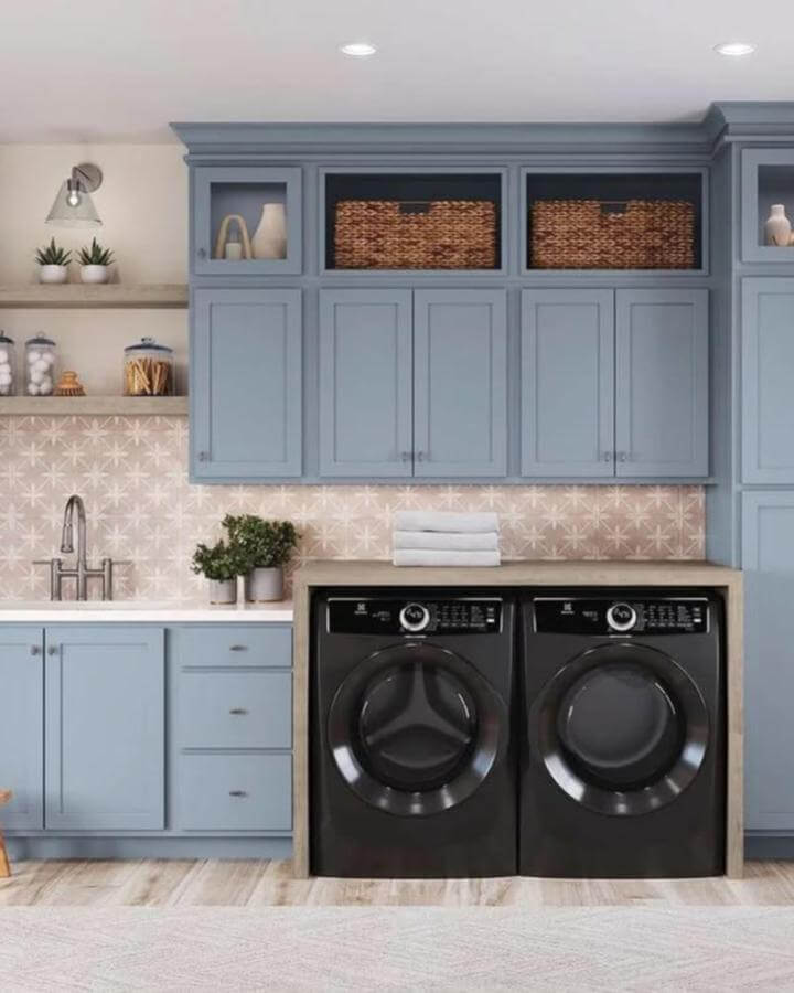 Soft dusty blue cabinetry laundry room from @butterflykitchenschicago with woven baskets and star-patterned tile backsplash.