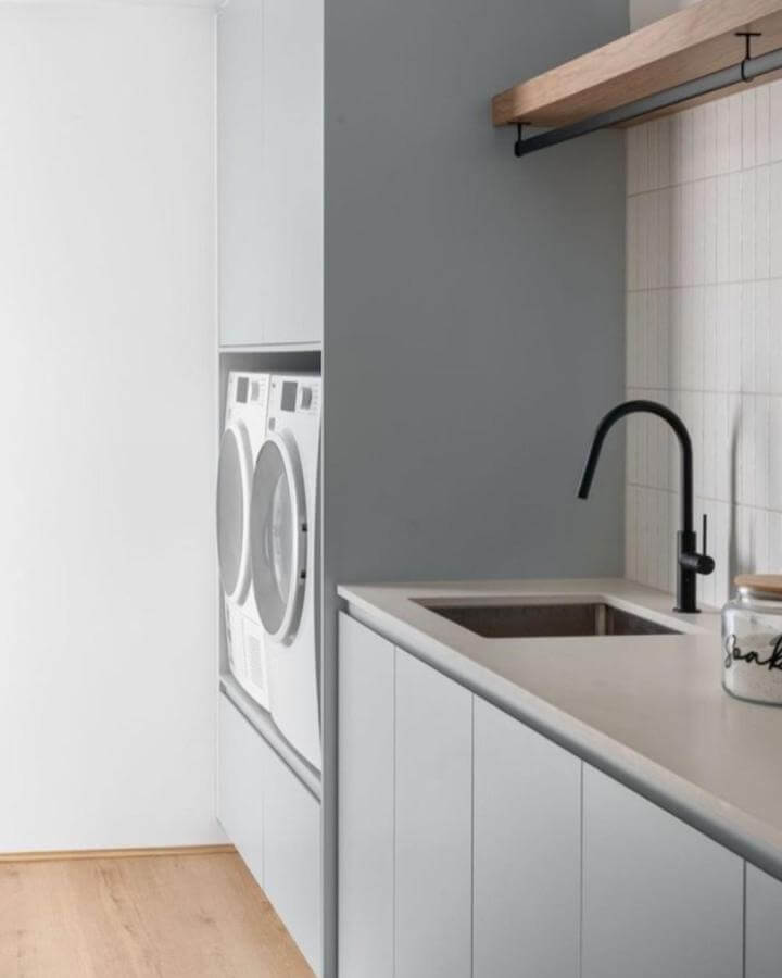 Light muted blue laundry area by @phoenixtapware with white cabinets, black faucet, and wood accents creating a calm, clean space.