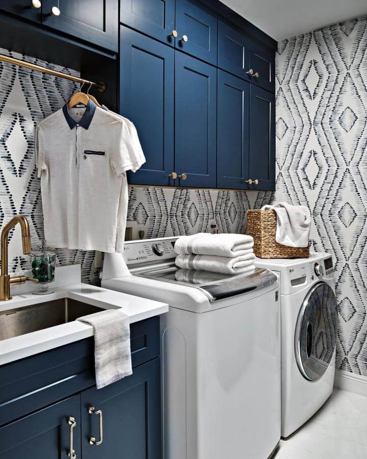 Navy cabinetry laundry room with geometric backsplash from @firefinish_interiors bright and inviting design.