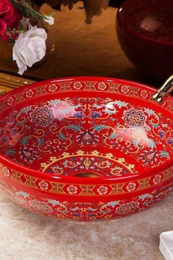 Boho bathroom featuring intricate red ceramic sink; explore boho bathroom ideas.