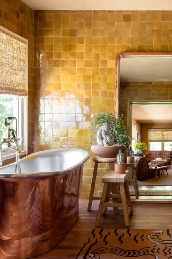 Freestanding copper tub in boho bathroom with eclectic decor; boho bathroom ideas.