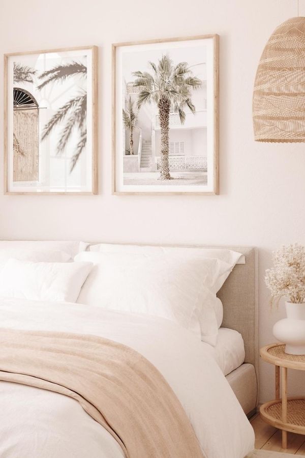 Minimalist bedroom featuring palm tree art, white bedding, and plants.