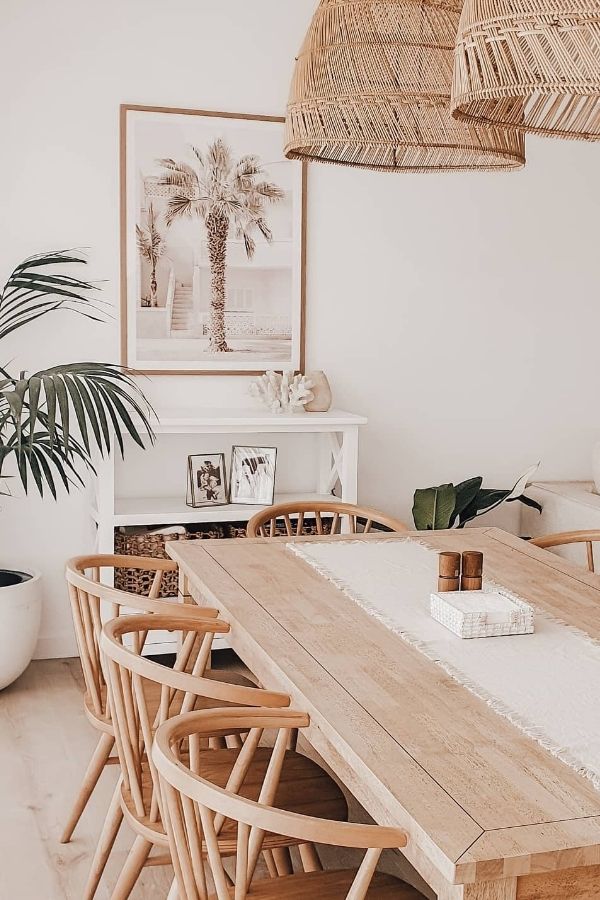 Cozy dining area featuring rattan lighting, wooden table, and plants.