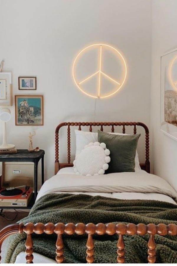 Neon peace sign light from @potterybarnteen casts vibrant glow, enhancing boho teenage girl bedroom ideas with joyful vibes.