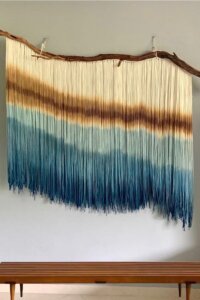 Colorful ombre macramé wall hanging with intricate knots and patterns.
