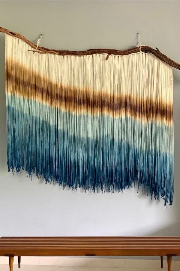 Colorful ombre macramé wall hanging with intricate knots and patterns.