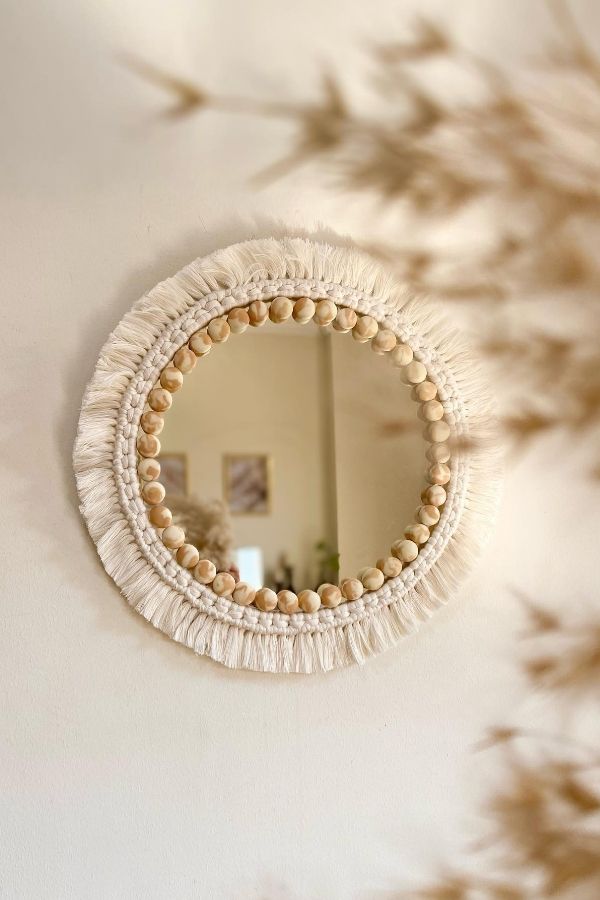 Macramé mirror with intricate knots, adorned with rustic wooden beads.