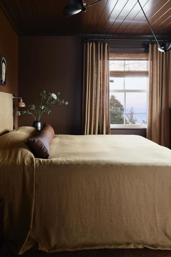 Vintage bedroom featuring dark wood paneling, antique furniture, cozy lighting.