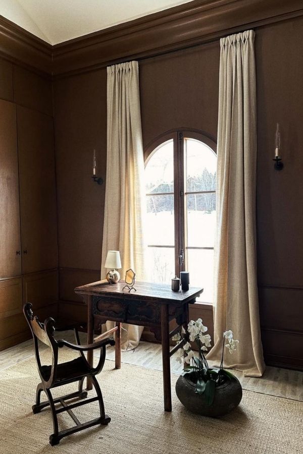 Cozy study room with wooden desk, bookshelf, chair, and plants.