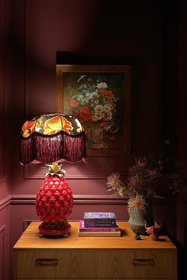 Vintage lamp with ornate details beside a vibrant floral painting.