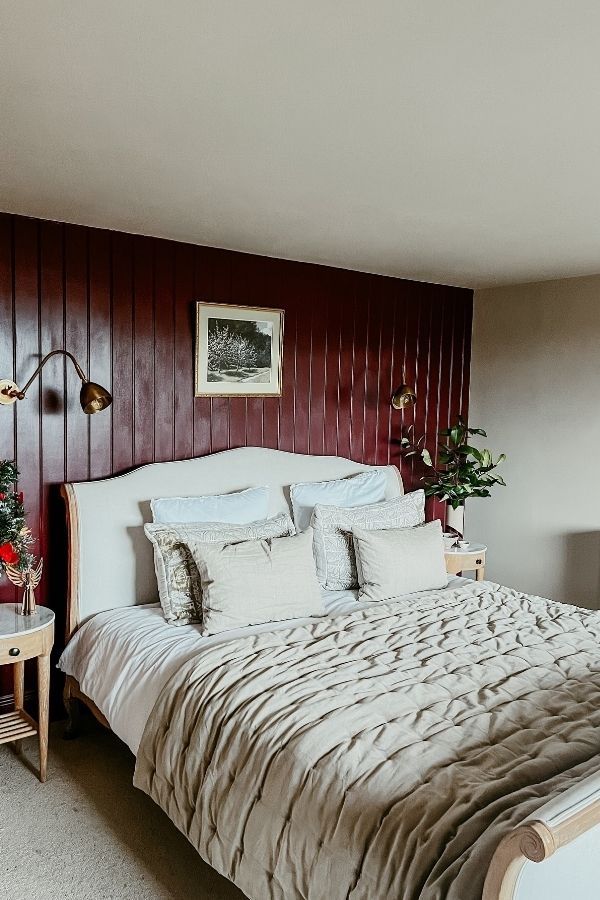 Cozy rustic bedroom featuring rich burgundy wood paneling throughout.