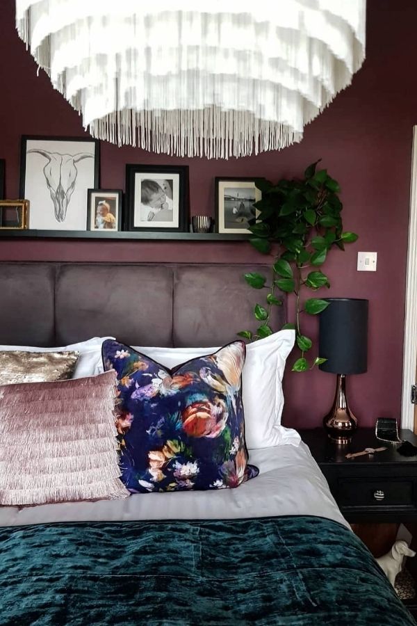 Cozy bedroom featuring a burgundy statement wall with artistic decor.