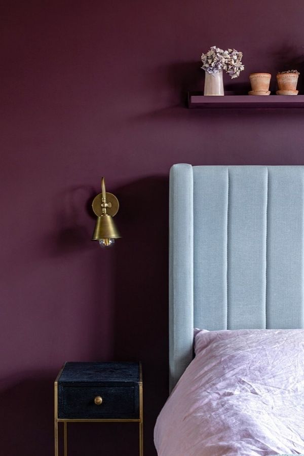 Minimalist bedroom featuring a striking burgundy accent wall and furnishings.