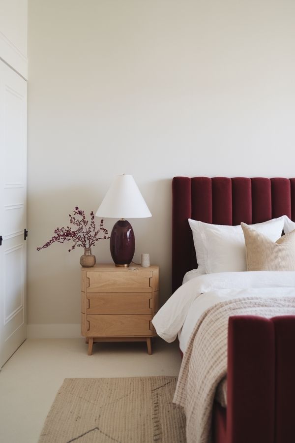 Minimalist bedroom featuring burgundy accents, clean lines, and simple decor.