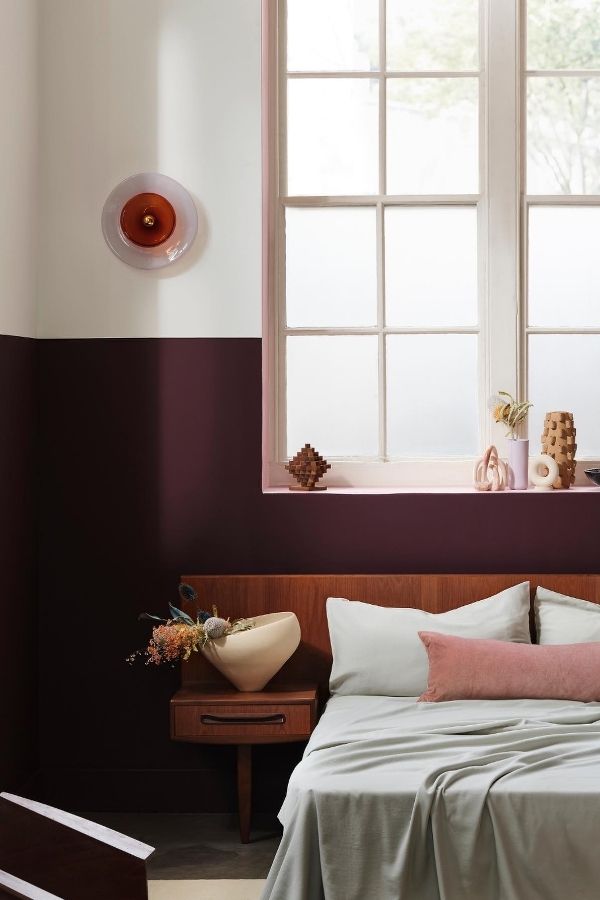 A stylish Mid-Century Modern bedroom with burgundy accents and furniture.