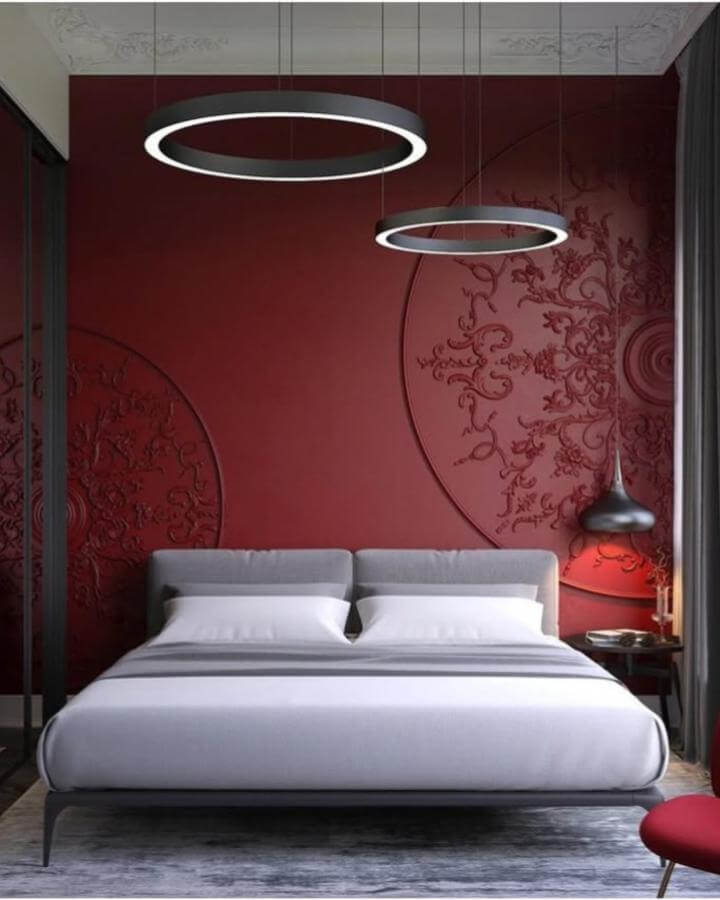 Cherry red textured wall with circular embossing behind modern grey bed and ring pendant lights by @jolauriedesign simple elegant bedroom ambiance