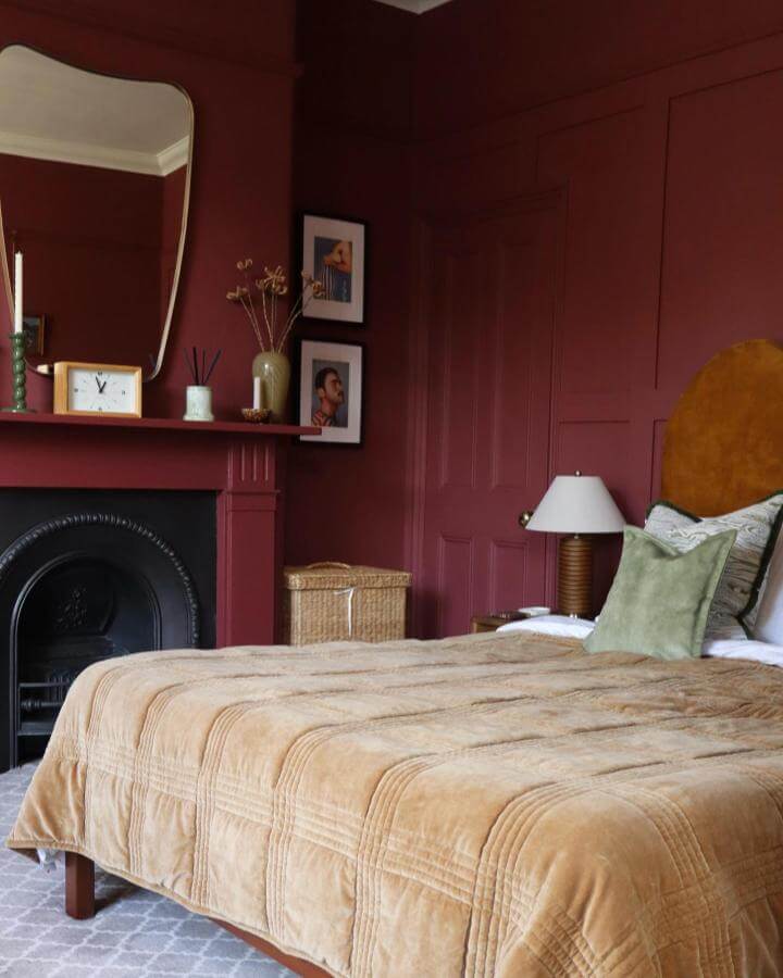 Velvet headboard and deep cherry walls bedroom with beige quilted bedspread and green accent pillow from @hectorsplace15. Cozy, warm, vintage-inspired decor.