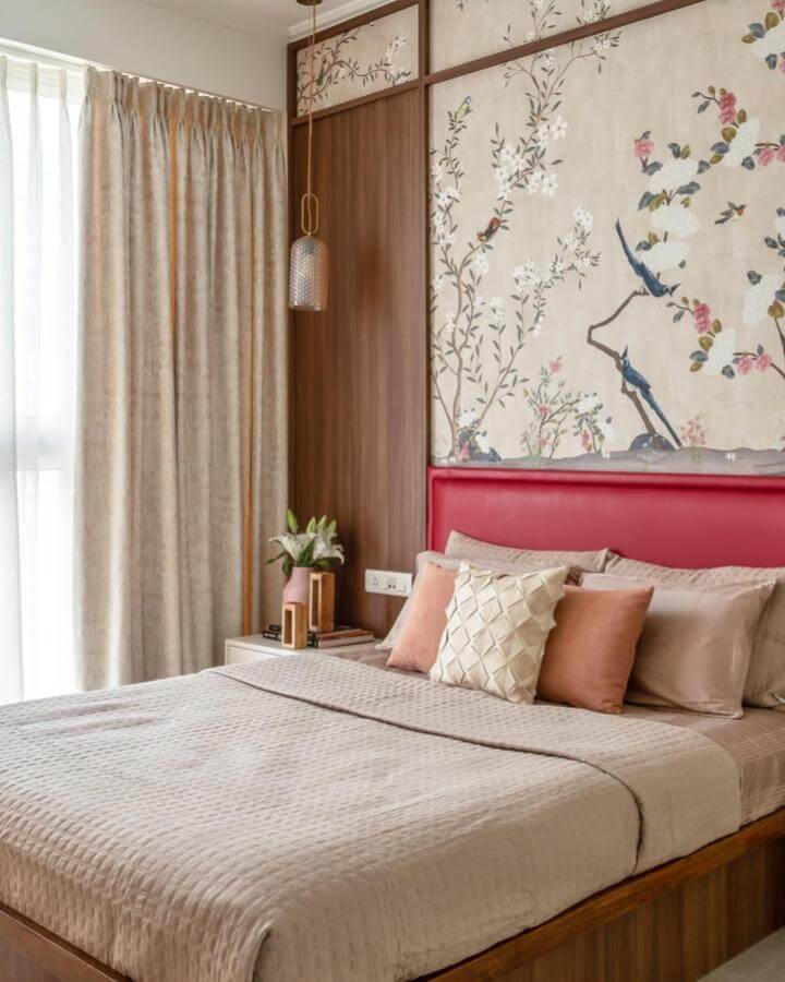 Cherry red leather headboard with soft beige bedding and floral wallpaper by @anuja.kambli creating a warm and elegant bedroom atmosphere