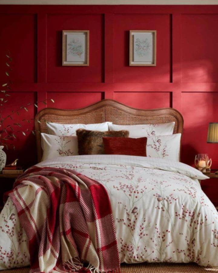 Rattan headboard bedroom with warm berry patterned bedding and cozy plaid throw in deep red tones by @aldiss_uk, inviting and layered style.