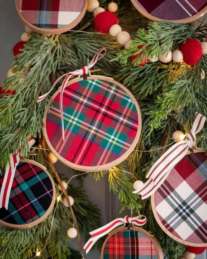 Plaid fabric ornament from @inspiredbycharm. Wooden embroidery hoop frames with striped ribbon hangers on evergreen wreath.