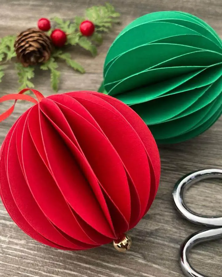 Red and green layered paper ornaments from @giftwrappinglove. Dimensional accordion-style baubles with gold caps.