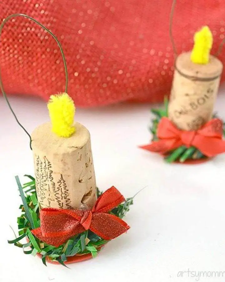 Wine cork candle ornaments from @artsymomma_amanda with yellow pom-pom flames and red ribbon bows.