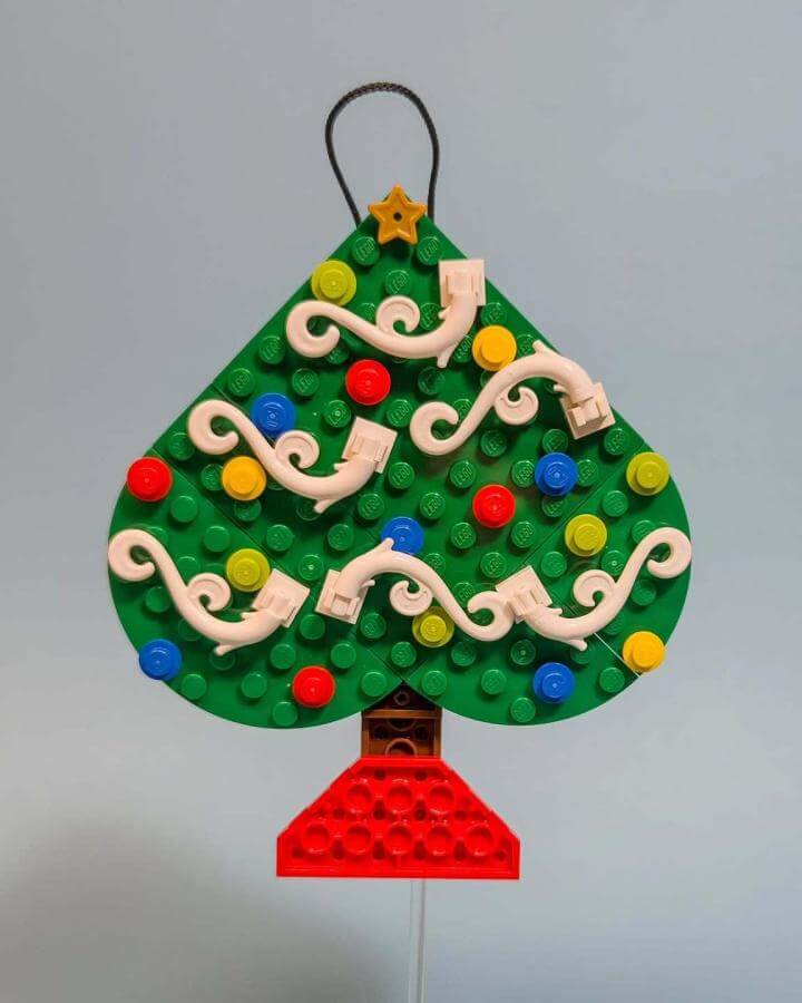 Green building block ornament from @moptoptrev with colorful baubles and white garland swirls.