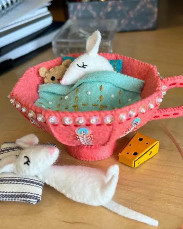 Coral felt teacup bed with miniature stuffed animals from @mmmcrafts. Pearl trim and embroidered mint blanket details.