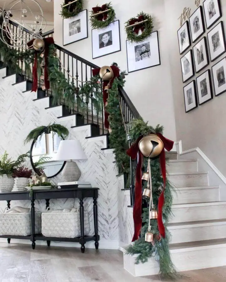 Luxurious staircase with oversized gold bells and pine garland from @tablefor5please. Burgundy ribbon accents.