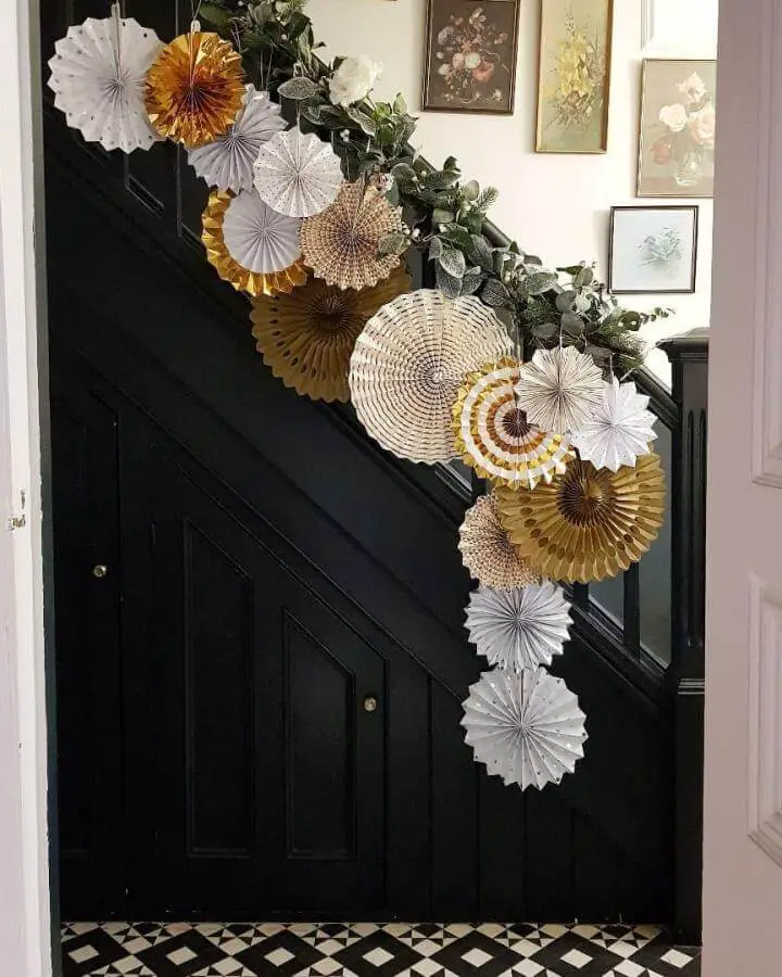Gold and white paper medallion christmas staircase garland ideas from @at_janes. Eucalyptus accents on black railing.