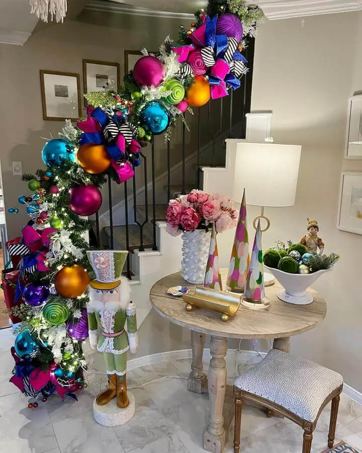 Colorful ornament garland from @shelleydobbsinteriors with magenta, turquoise, and lime accents on black stair railing.