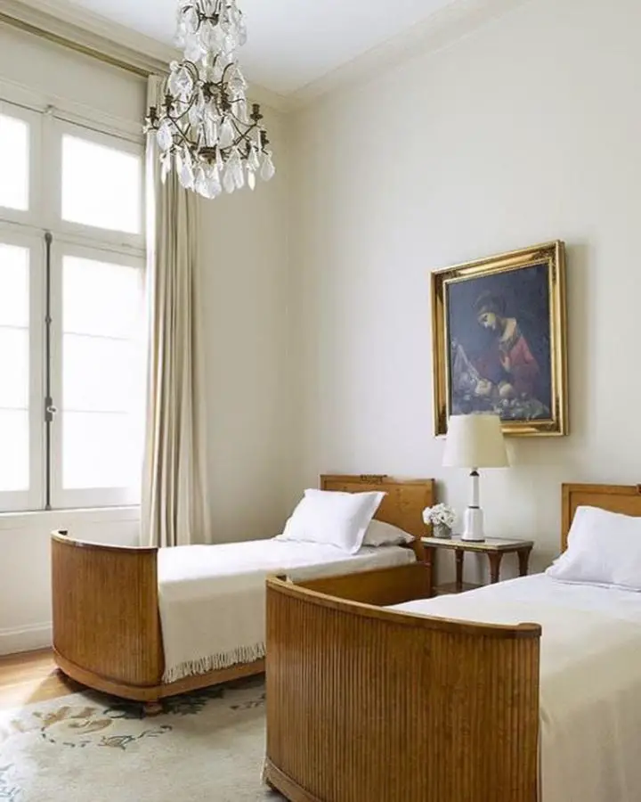 Ornate crystal chandelier bedroom from @vaughnmillerstudio showcasing classic bedroom ideas with twin beds and vintage artwork.