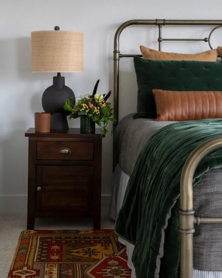 Emerald velvet bedding and brass bed frame from @trussinteriors. Cognac leather pillow adds warmth to the rich color palette.
