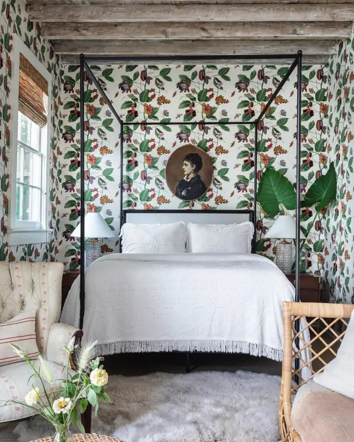 Botanical wallpaper bedroom from @logankilleninteriors. Black four-poster bed with white bedding and vintage portrait.