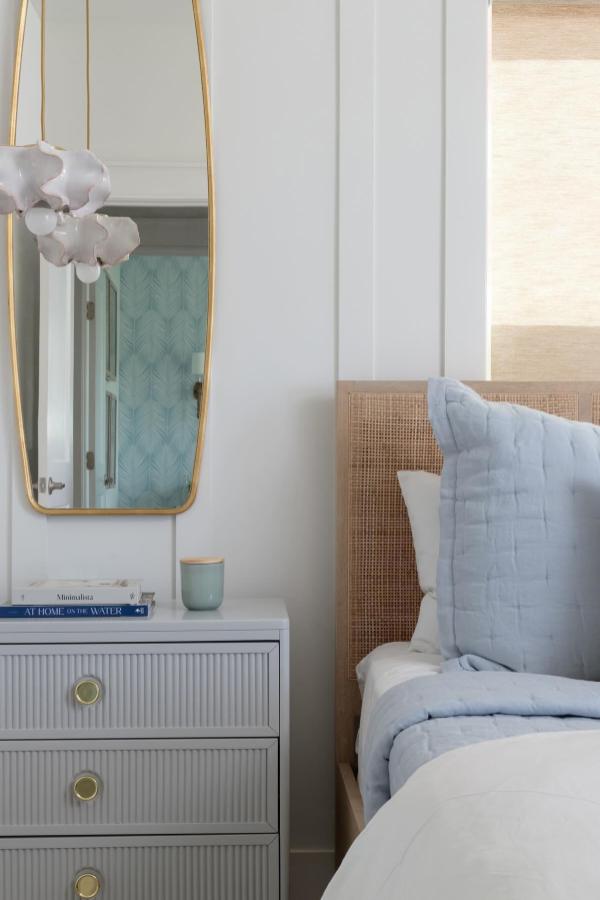 Light blue bedding and woven cane headboard from @jenniferkizzeedesign showcasing coastal bedroom ideas with natural textures.