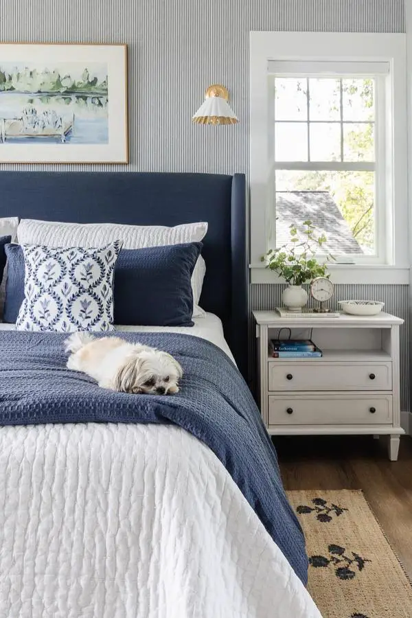 Navy upholstered headboard from @lilypadcottage. Paired with white quilted bedding and blue patterned pillows.