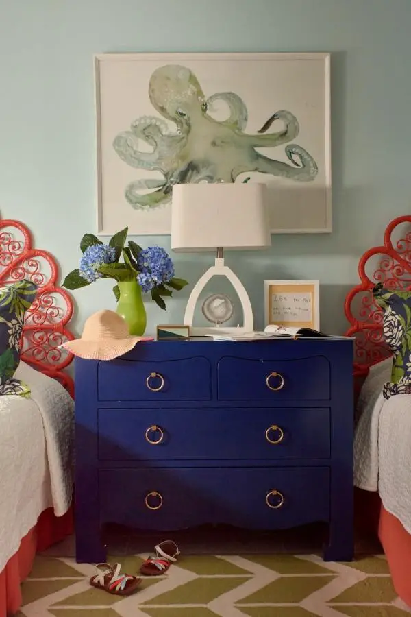 Navy blue dresser from @maalleninteriors featuring octopus art and coral accents for coastal bedroom ideas inspiration.