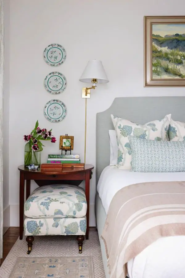 Sage green upholstered bedroom from @vpidesignatlanta. Features turquoise decorative plates and brass swing-arm lamp.