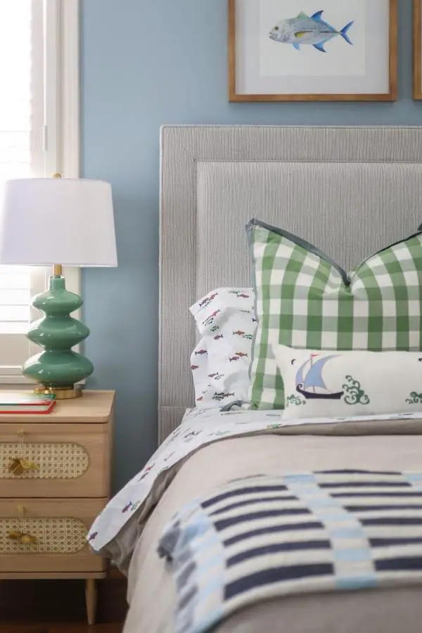 Green gingham pillows and striped bedding from @medinainteriors. Coastal bedroom mixing nautical patterns with light blue walls.