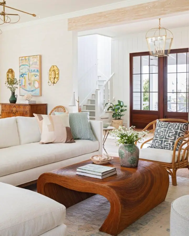 Curved bamboo coffee table from @allisonelebashinteriors with white sectional sofa and sage green accents.